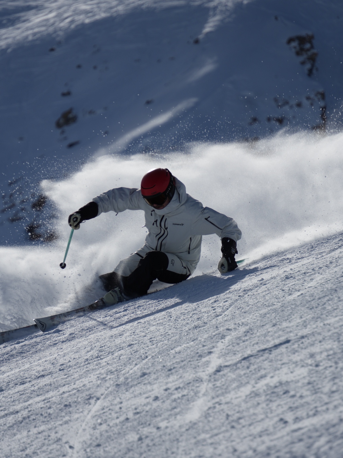 Luc en veste blanche et casque rouge, en virage dans la poudreuse